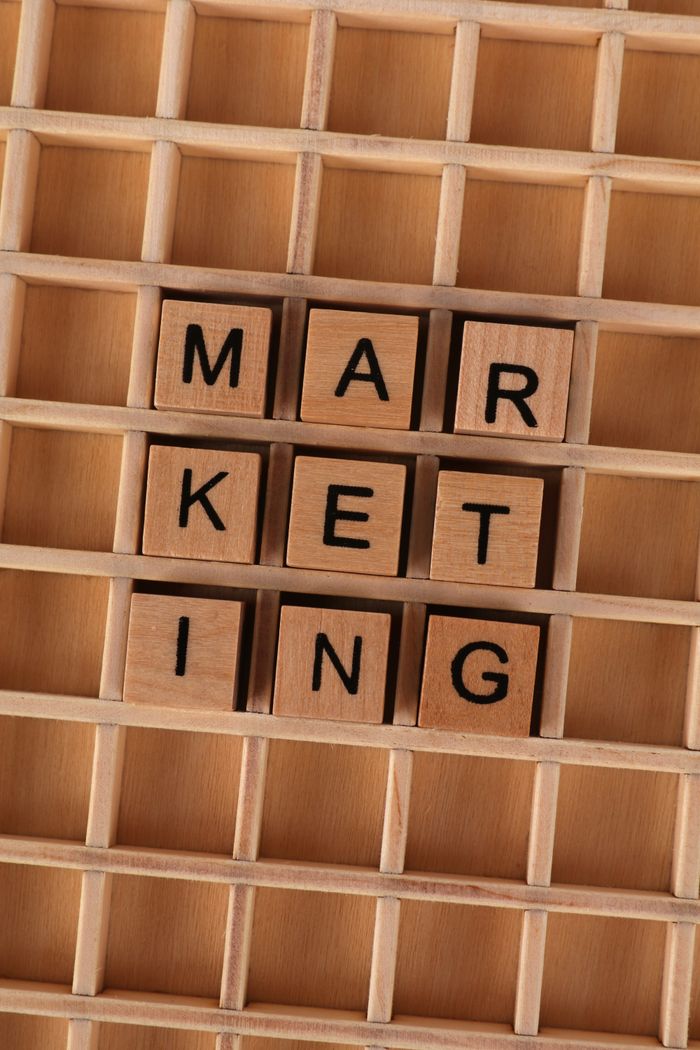 Des lettres en bois disposées pour former le mot marketing sur une grille en bois, illustrant une stratégie commerciale.